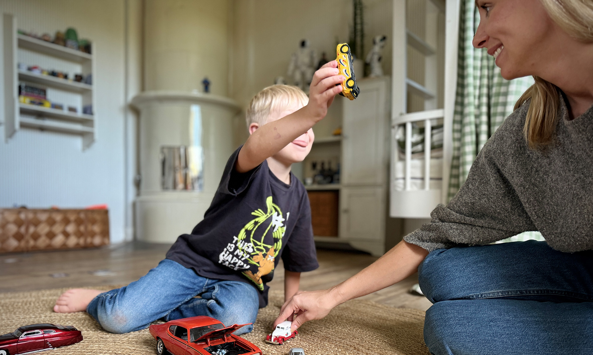 A mother sitting on the floor playing with cars together with her son